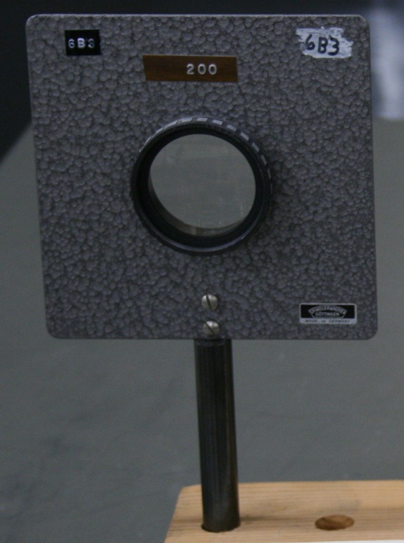 A golf-ball-sized 200 mm lens within a square barrier mounted on a stem.