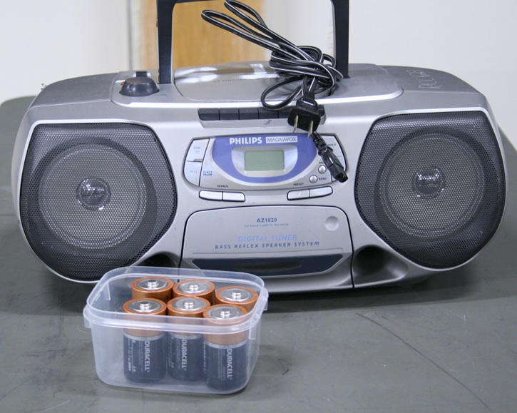 Portable stereo radio and CD player with A/C power cord and box of 6 C batteries.