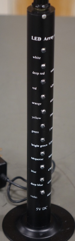 A narrow black tower with eleven different-colored LEDs moutned vertically and a control switch on the top.  From top to bottom, colors are: white, deep red, red, orange, yellow, green, bright green, turquoise, blue, deep blue, and violet.