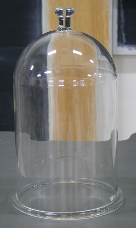 Clear glass cylinder a foot high with domed cap and knob.