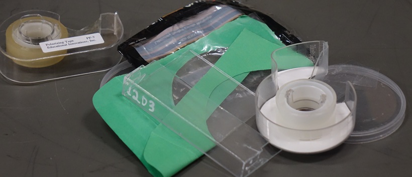 A collection of clear plastic objects, including wrappers, tape dispensers, a Pringles lid, and a cassette tape holder.