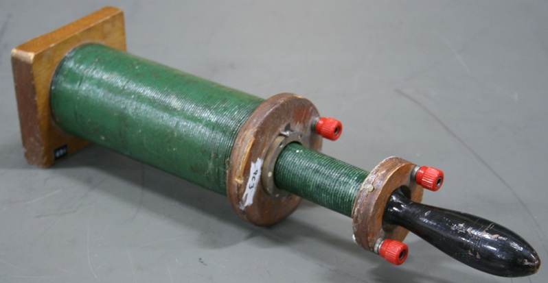 An iron-core solenoid with a rounded handle fits neatly inside a larger air-core solenoid.  Each coil has a pair of banana-plug terminals.
