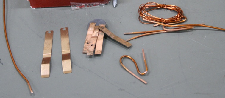 A collection of copper objects.  Some are sections of thick wire, some are thin sheet strips.