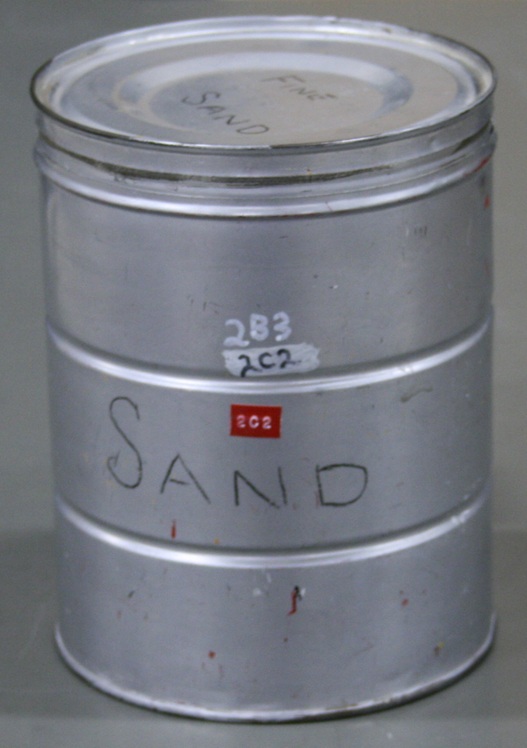A large metal can reads "SAND" on its side and "FINE SAND" on its lid.