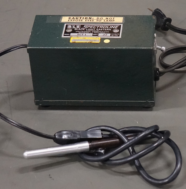 A finger-length mercury lamp in aluminum shielding, connected by cable to a transformer box with a power switch.