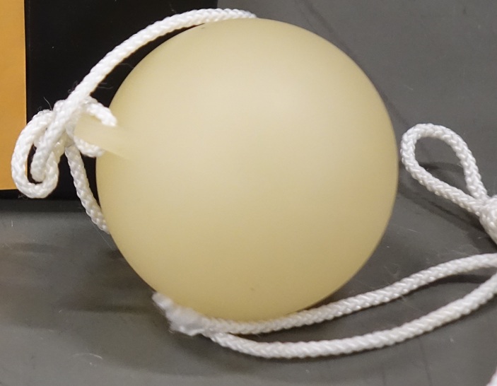 A tennis-ball sized plastic ball with a cord attached to a protrusion.