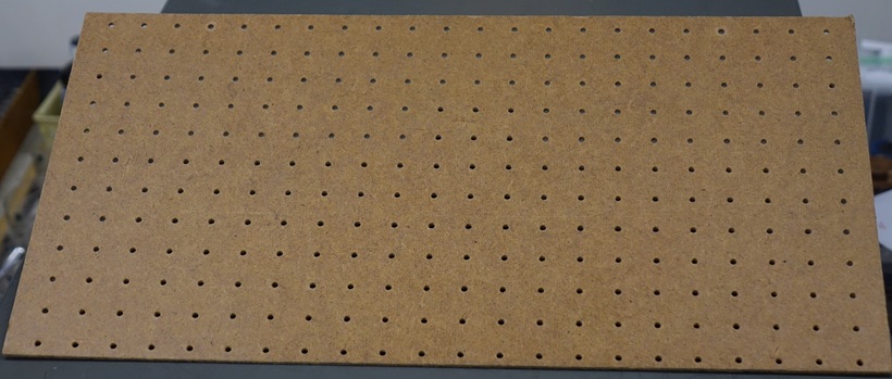 A sheet of pegboard one foot by two feet, with an inch separation between the holes.