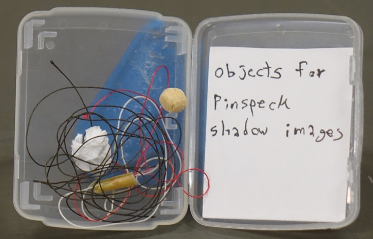 A memory card box displays three tiny objects tied to threads.  A note reads "objects for pinspeck shadow images".