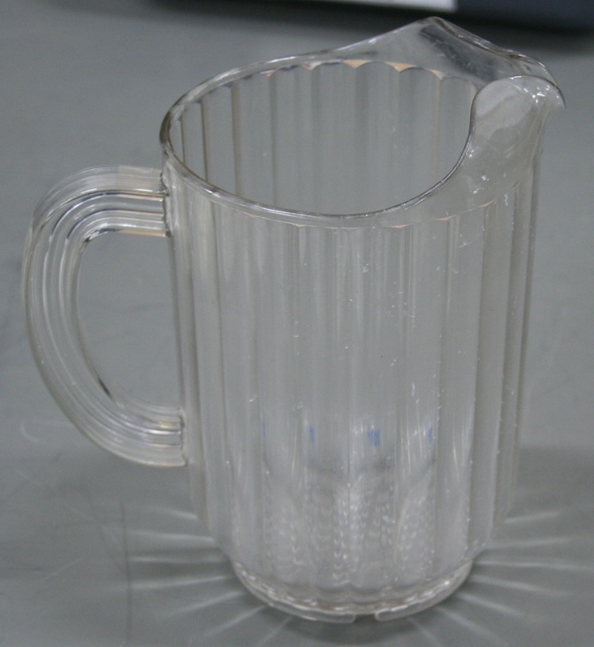 A clear plastic pitcher with vertical ribbing and flaring spout.