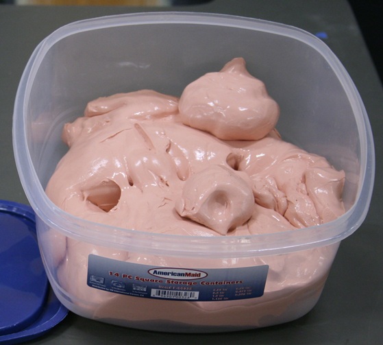 A square 5-liter container almost half filled with Silly Putty.