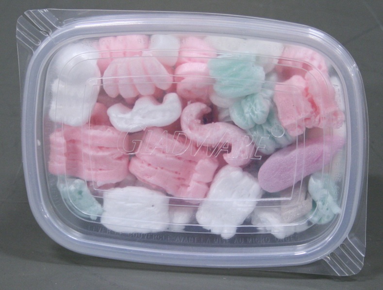 A rectangular 24-ounce clear plastic container stuffed with foam packing peanuts.