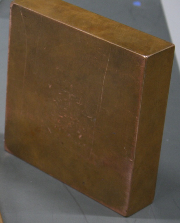 A solid copper block eight inches square and two inches thick.