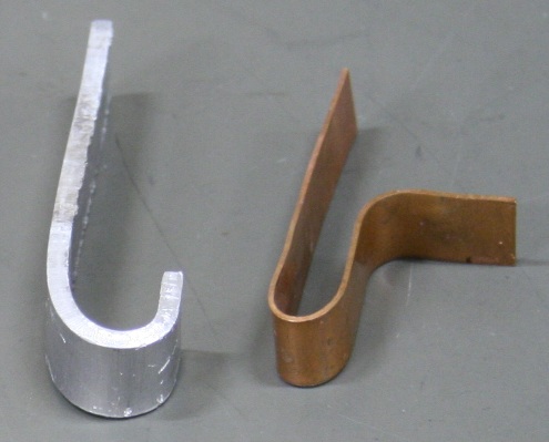 A pair of bent metal strips, one zinc and the other copper.  The zinc is J-shaped, while the copper is closer to a U with a tail.