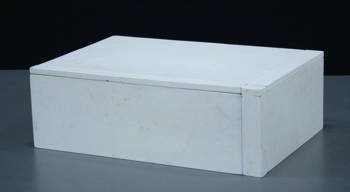 White painted wooden rectangular block viewed from an angle, showing it is assembled from multiple pieces