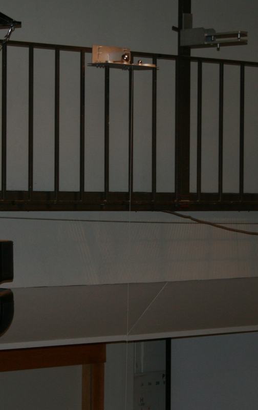 Close-up of the release platform on the catwalk railing, showing the ball bearings loaded on the platform with the railing and ceiling structure visible