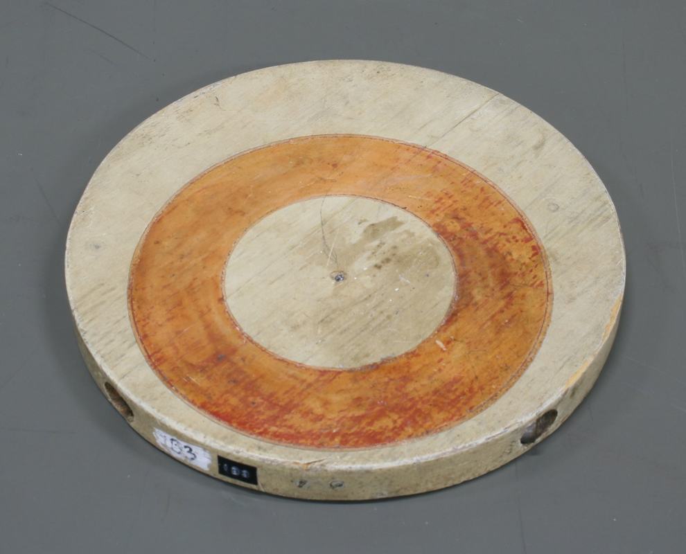 Wooden disk with concentric orange ring centered on the geometric center