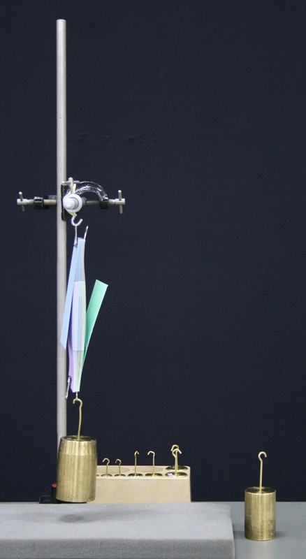 Ring stand with rod and ring clamp holding interleaved cards, brass masses on the bench below, and packing foam at the base