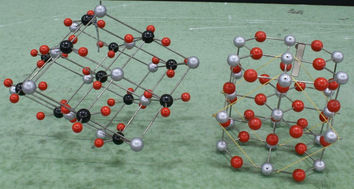 Two ball-and-stick models with silver/gray and red spheres; left has orange-highlighted bonds in a layered arrangement, right has yellow-highlighted features in a three-dimensional lattice