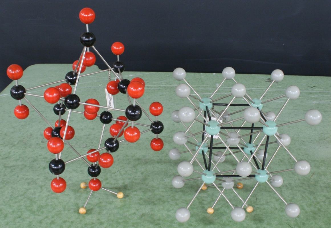 Left: ball-and-stick model with black and red spheres; right: model with white and light blue/turquoise spheres showing a cubic lattice structure