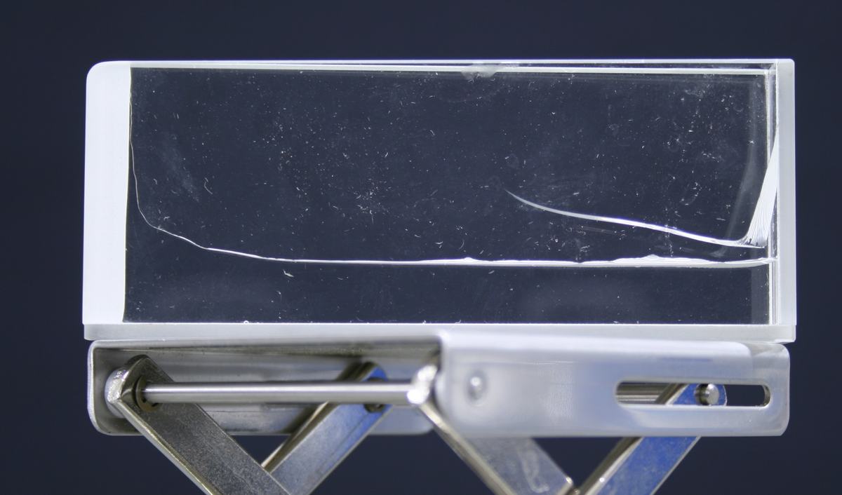 Glass wedge apparatus on a lab jack: two glass plates forming a narrow wedge, with a visible capillary curve where water rises higher at the narrow end
