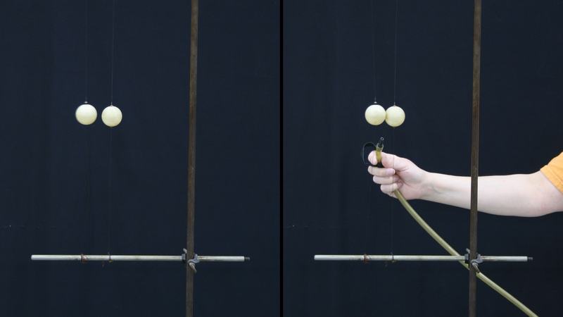Two-panel photo: Left — two ping-pong balls hanging from strings on a rod stand at rest. Right — a hand holds a hose with barb nozzle positioned between the balls.