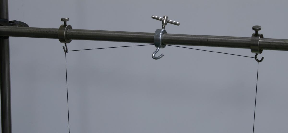 Close-up of the horizontal rod showing three ring clamps with hooks and thumbscrews; the center clamp holds the string midpoint, and the two outer clamps serve as adjustable pivot points