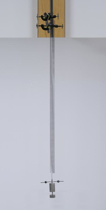 Wilberforce pendulum: long helical spring suspended from a rod and clamp system, with a cylindrical brass bob at the bottom fitted with a horizontal cross-bar carrying adjustable masses