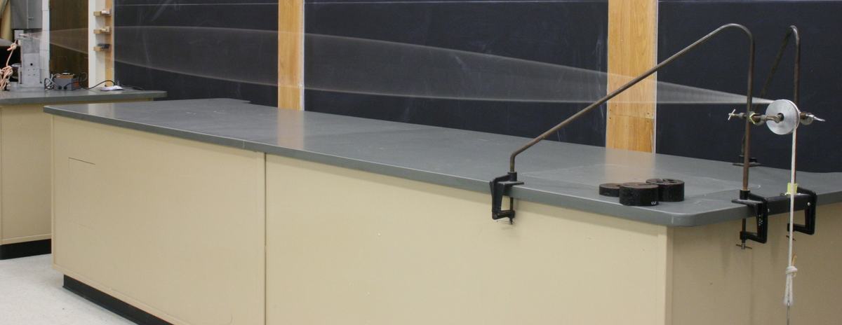 Wide view of rope stretched horizontally across laboratory bench showing straight rope configuration before motor activation