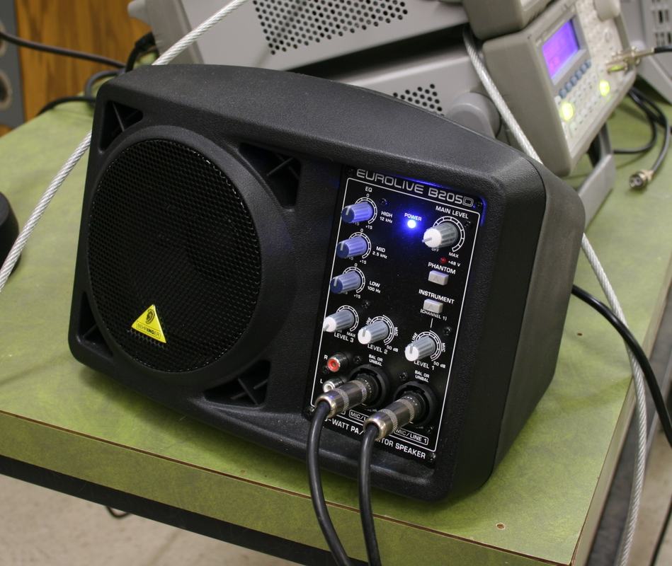 Behringer Eurolive B205D powered monitor speaker with two audio cables connected to input jacks on the front panel