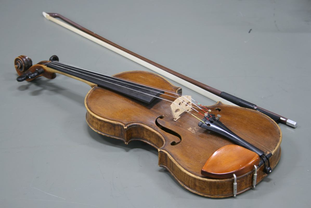 Violin with bow resting on gray surface
