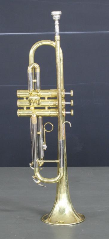 B-flat trumpet standing on its bell, showing brass body, three piston valves, and silver-plated mouthpiece