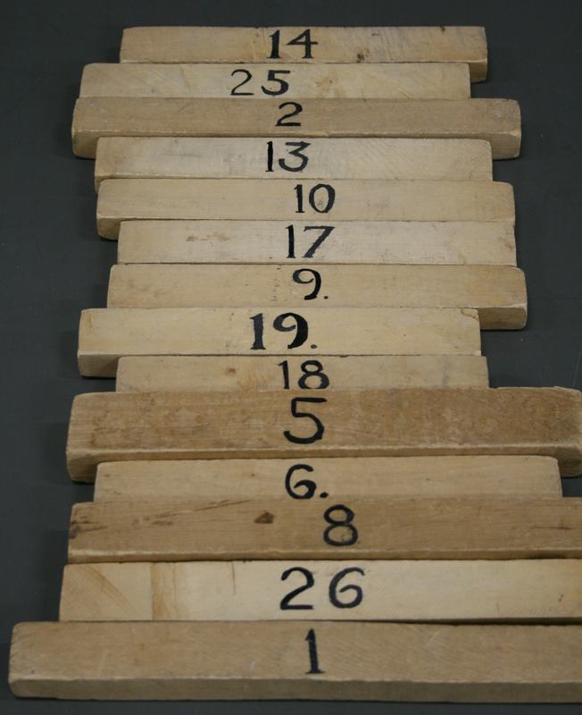 Close-up of numbered wooden bars of varying lengths stacked and arranged by size, showing numbers 1 through 26