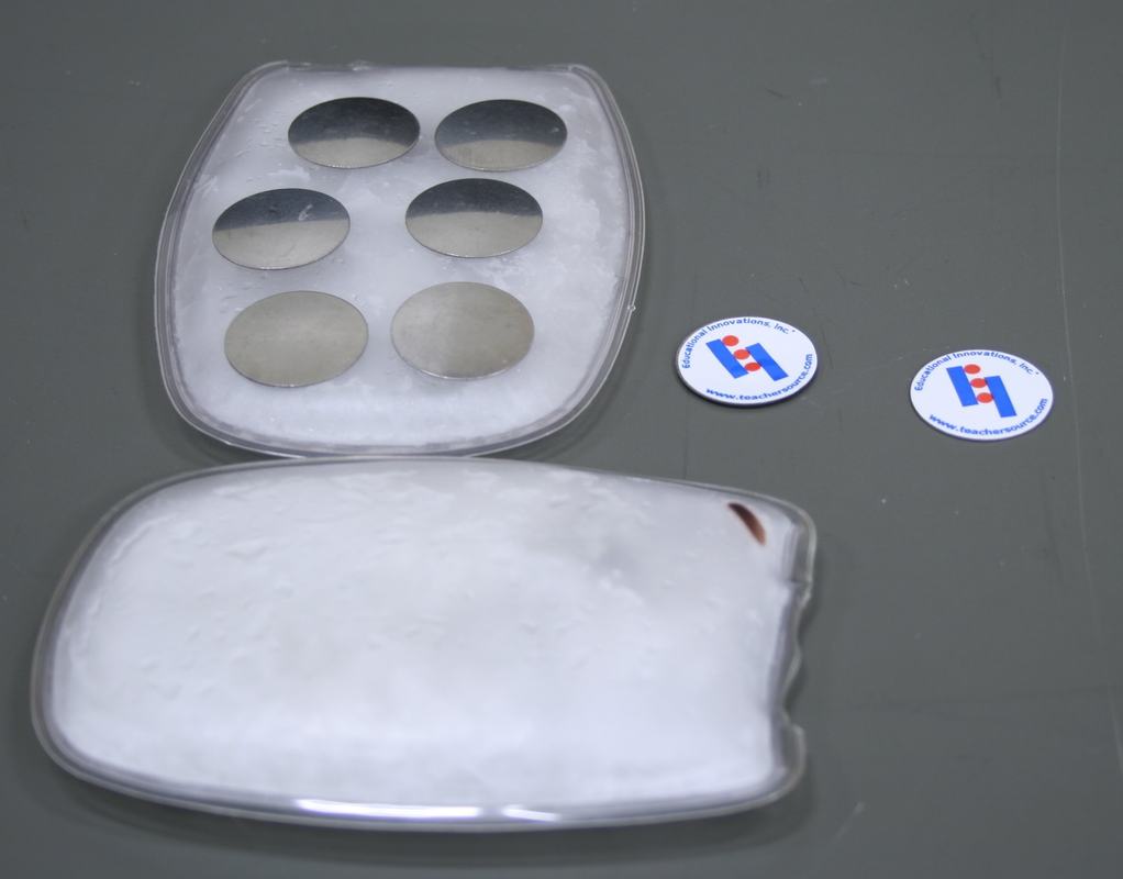 Six bimetallic discs on a crystallized reusable heat pad in a clear plastic case, with a second heat pad below and two small Educational Innovations logo discs to the right