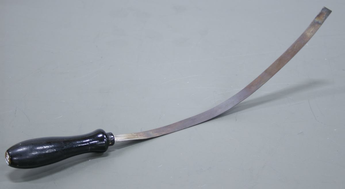 Same bimetallic strip curved into an arc after heating, with heat discoloration visible on the metal