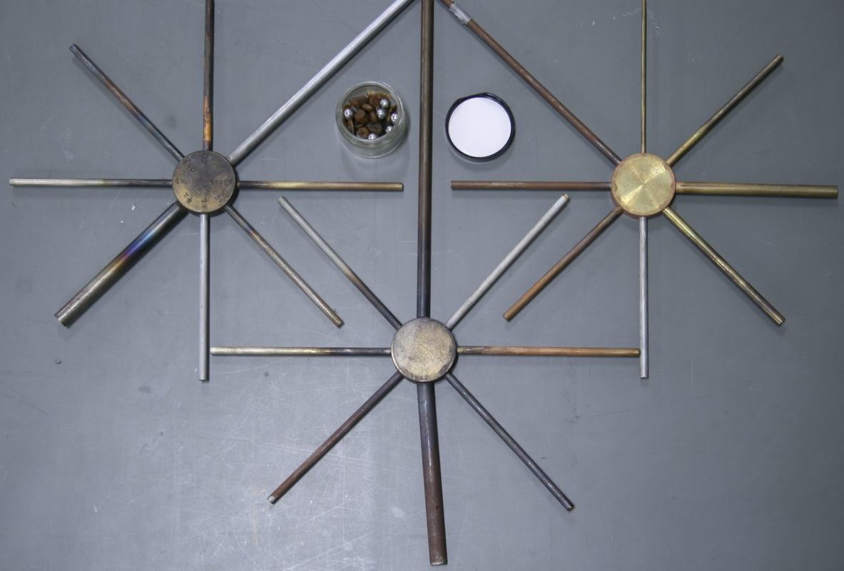 Three star-shaped conduction rod arrays laid flat on a surface, with a small glass jar of waxed steel balls between them