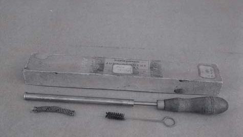 Fire syringe with metal plunger and wooden handle, storage box, and small cleaning brushes