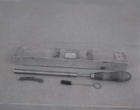 Fire syringe with metal plunger and wooden handle, storage box, and small cleaning brushes