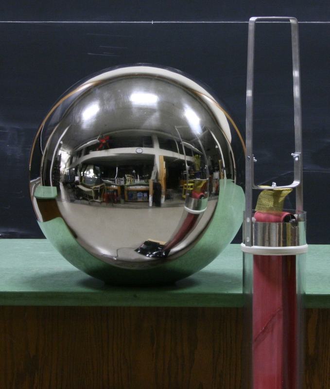 Large polished chrome sphere on a red insulating column with a discharge wand visible to the right