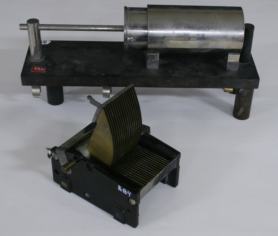 Two variable capacitors: a large enclosed cylindrical air capacitor on a black base (rear) and an open-frame air variable capacitor with interleaved semicircular plates (front)