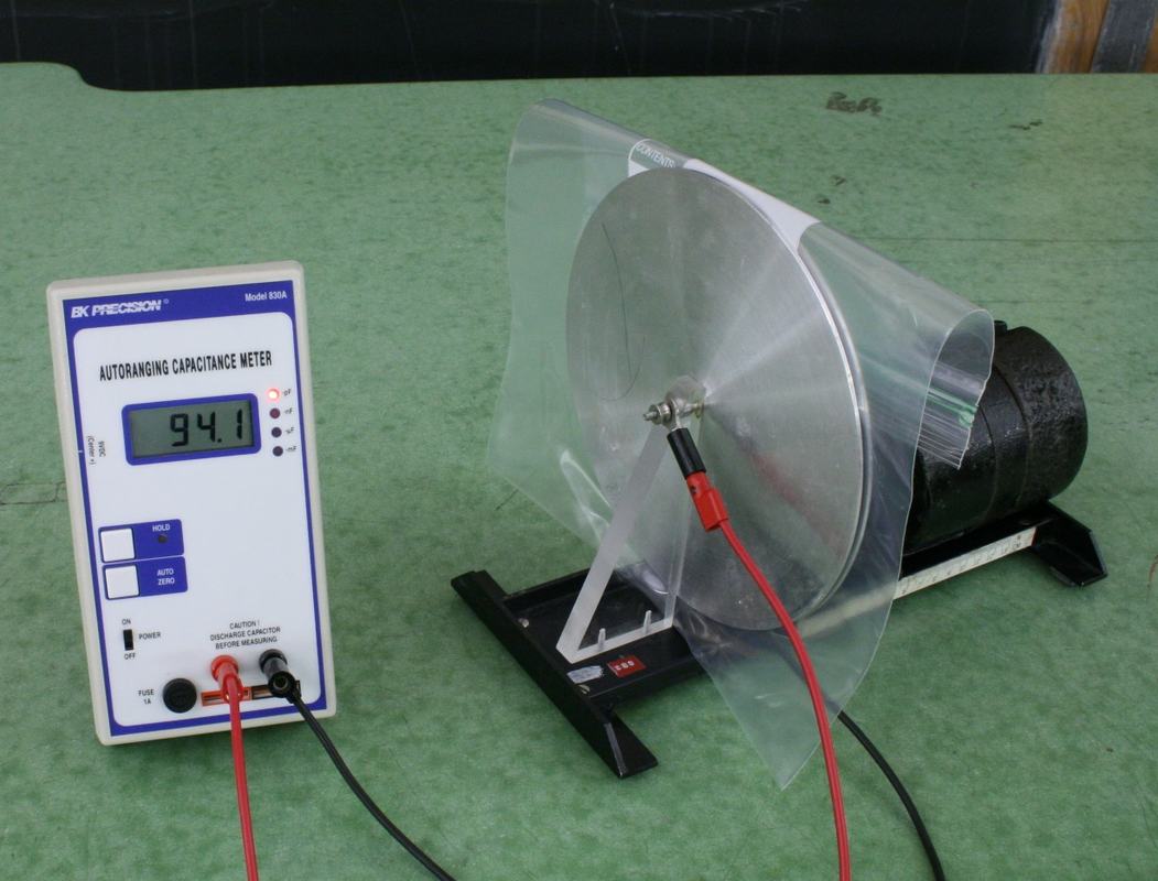 Same capacitor setup with water-filled freezer bag between plates, BK Precision capacitance meter now displaying 94.1 nF