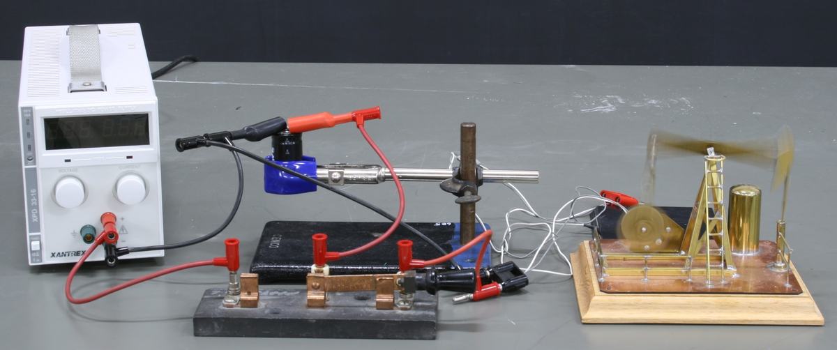 Same setup with power supply display off, SPDT switch flipped to discharge position, oil rig in motion (slight blur visible on the pump arm)