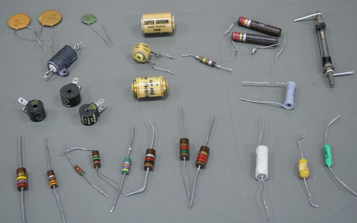 Collection of resistors and passive components including color-banded carbon and metal film resistors of various wattages, wire-wound resistors (one labeled Super Davohm), white ceramic power resistors, small black potentiometers, disc capacitors, and a wire-wound inductor
