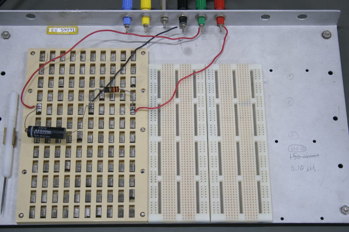 Close-up of breadboard module with resistor array, electrolytic capacitor, and wiring to colored binding posts. Handwritten label reads "330 ohms" and "0.10 μs"