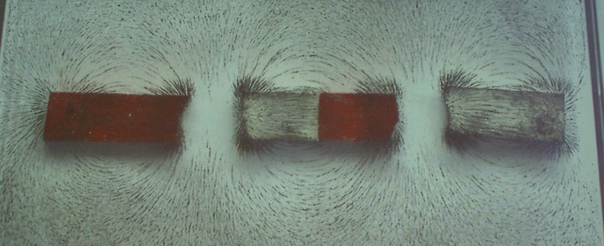 Four bar magnets arranged in a cross pattern with red and blue magnets, iron filings showing complex two-dimensional field superposition