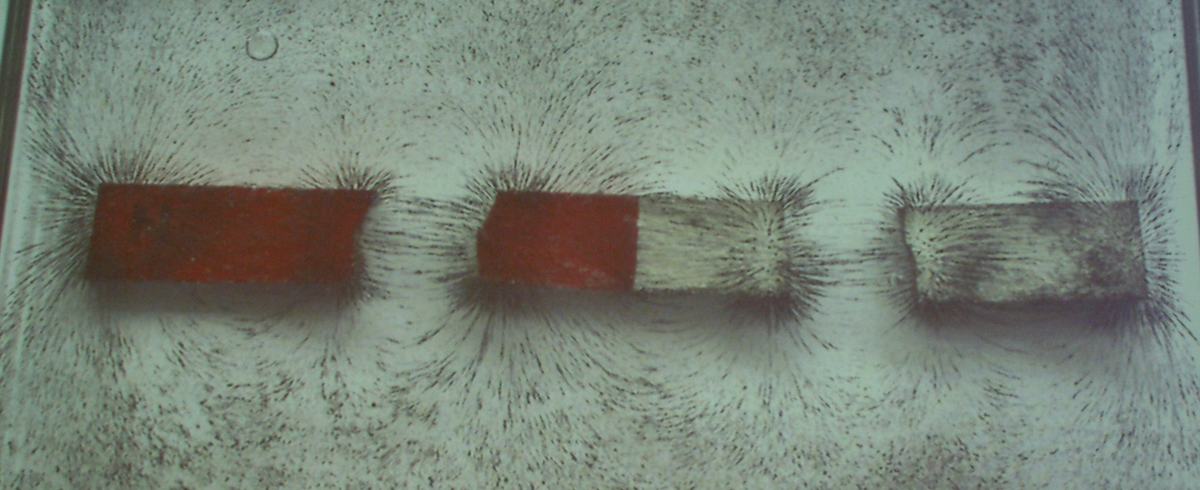 Three bar magnets arranged in a row with iron filings showing the superposed field pattern, with visible pole interactions between adjacent magnets