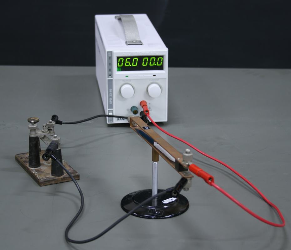 Same apparatus with power supply set to 06.0 V and 00.0 A (no current flowing), compass needle aligned with Earth's field inside the copper loop