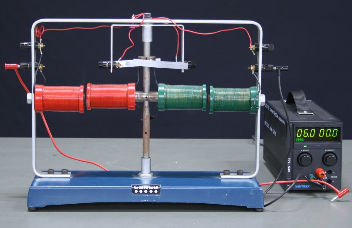 Same CENCO motor-generator at rest: armature coil clearly visible between red and green field coils, power supply reads 6.0V, 00.0A