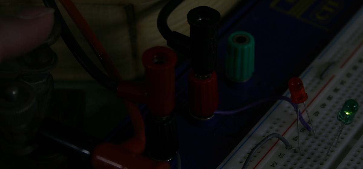 Close-up of breadboard with green LED illuminated and red LED dark