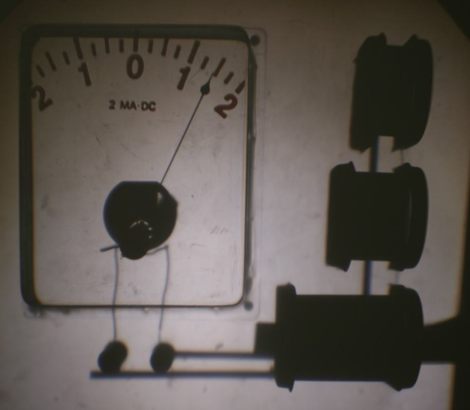 Overhead projection showing galvanometer face (2 mA DC, scale -2 to +2) with silhouettes of three coils visible to the right
