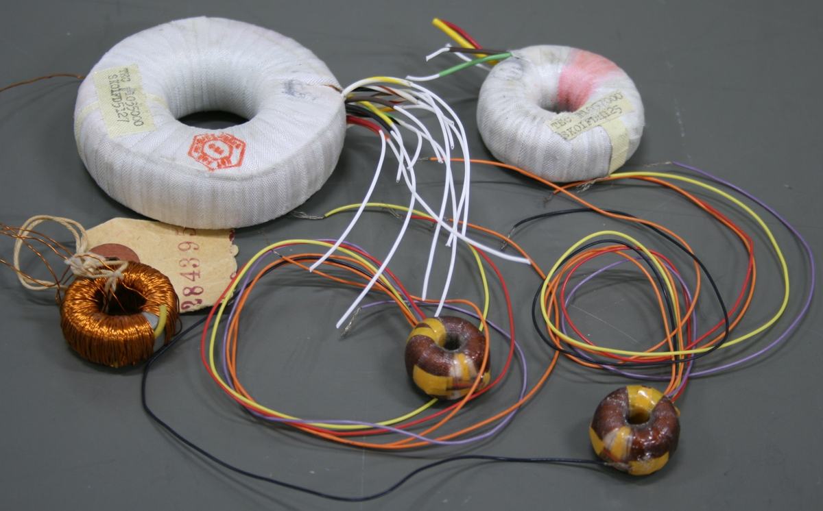 Several toroidal transformers with fabric-wrapped cores and multiple colored wire leads (white, orange, yellow, red, black), plus smaller copper-wound inductors